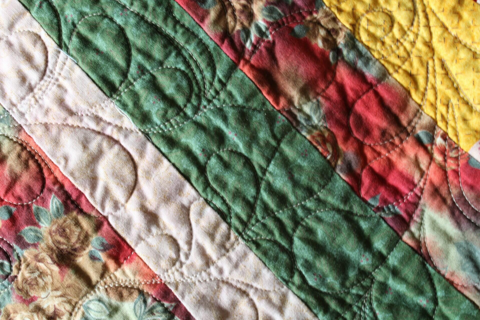 A green, red and yellow quilt with decorative stitching.
