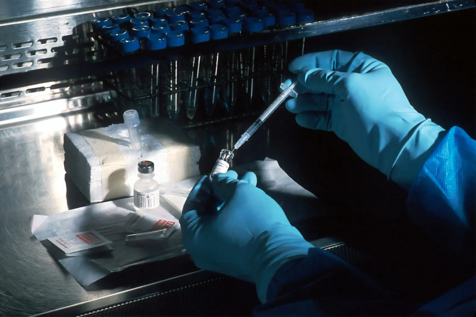 person working in a lab injecting a liquid into a test tube