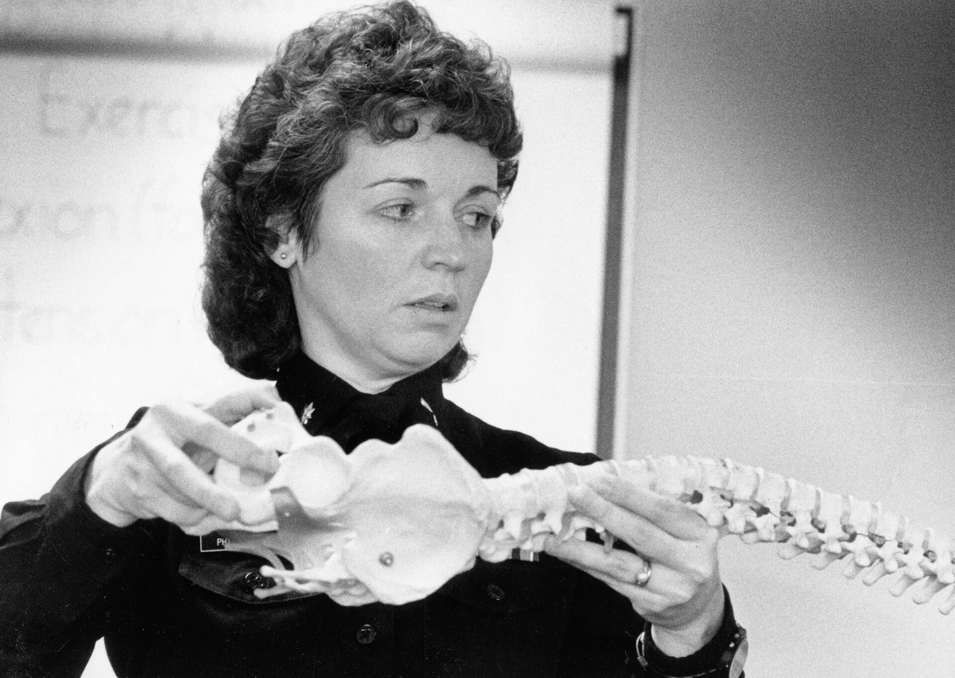 black and white image of a woman holding a model of a skeleton.